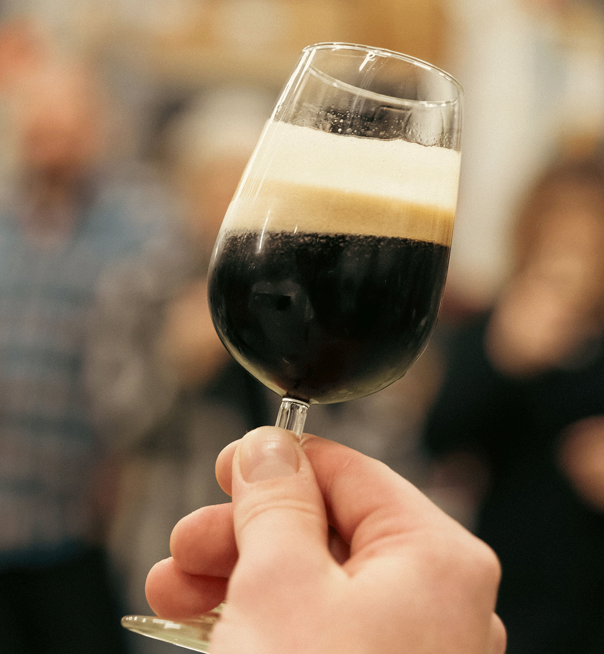 Degustazione di birra artigianale scura con densa schiuma.